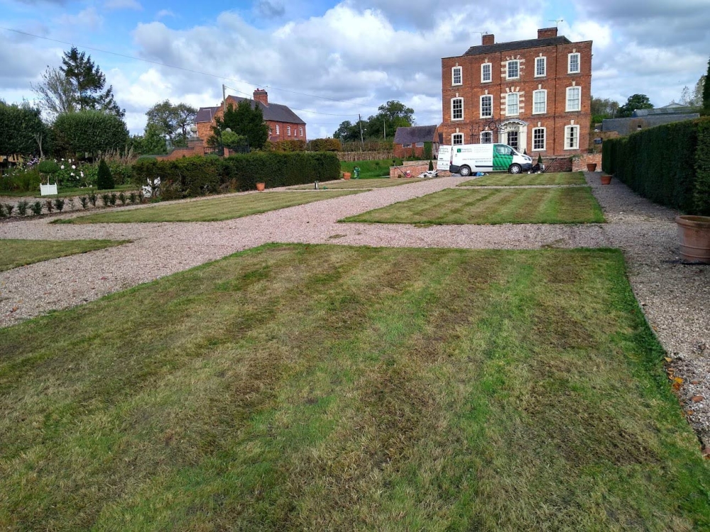 This image is of a large lawn benefiting from lawn services with one of of vans in the background